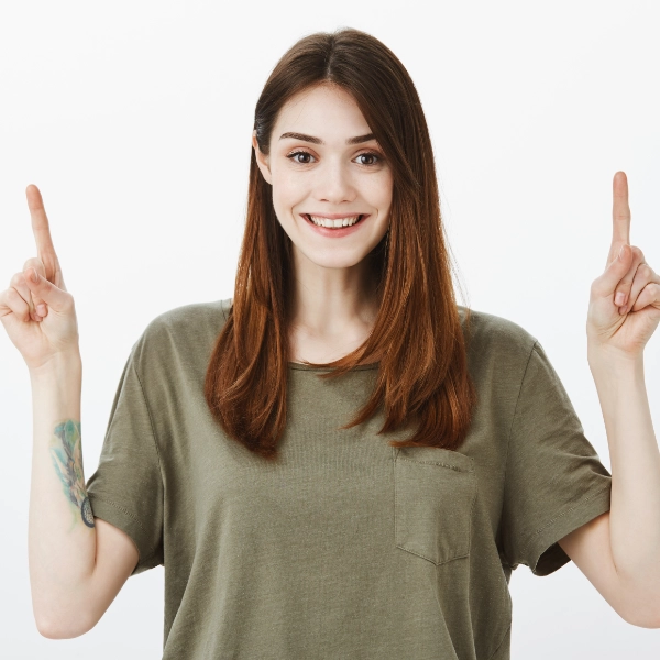 Mujer sonriendo y apuntando hacia arriba con ambos dedos